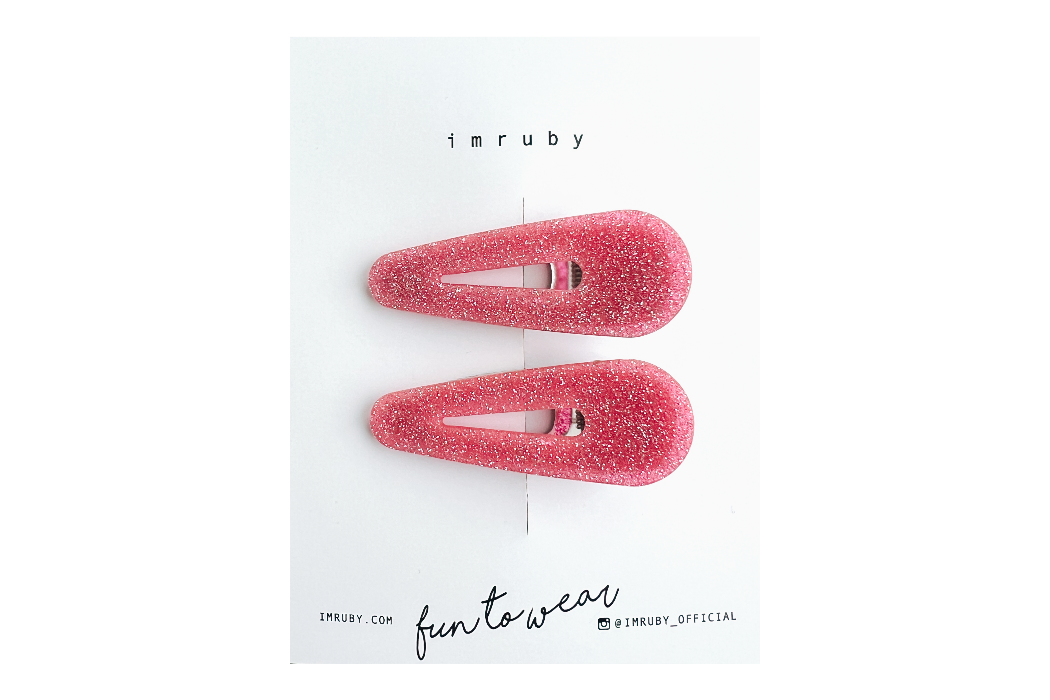 Hi! I'm LEIA, a set of two pink glitter teardrop clips.

Sparkly, sweet, and always in the mood to shine. I hold your hair in place with just the right grip — no pulling, no slipping. Lightweight and shaped to stand out, even when you're keeping it casual. Clip me in and carry on.