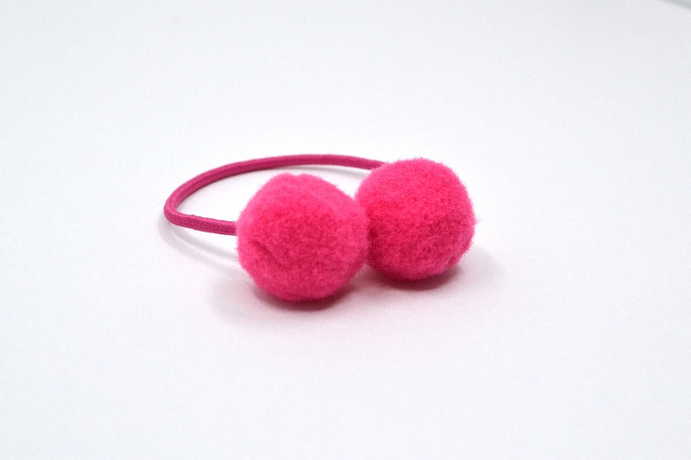 Hi! I'm BRUNA, a bright pink elastic hair ties set.  Be on trend with this set of pom hair ties! This 2 pack of hair ties comes in bright pink. 